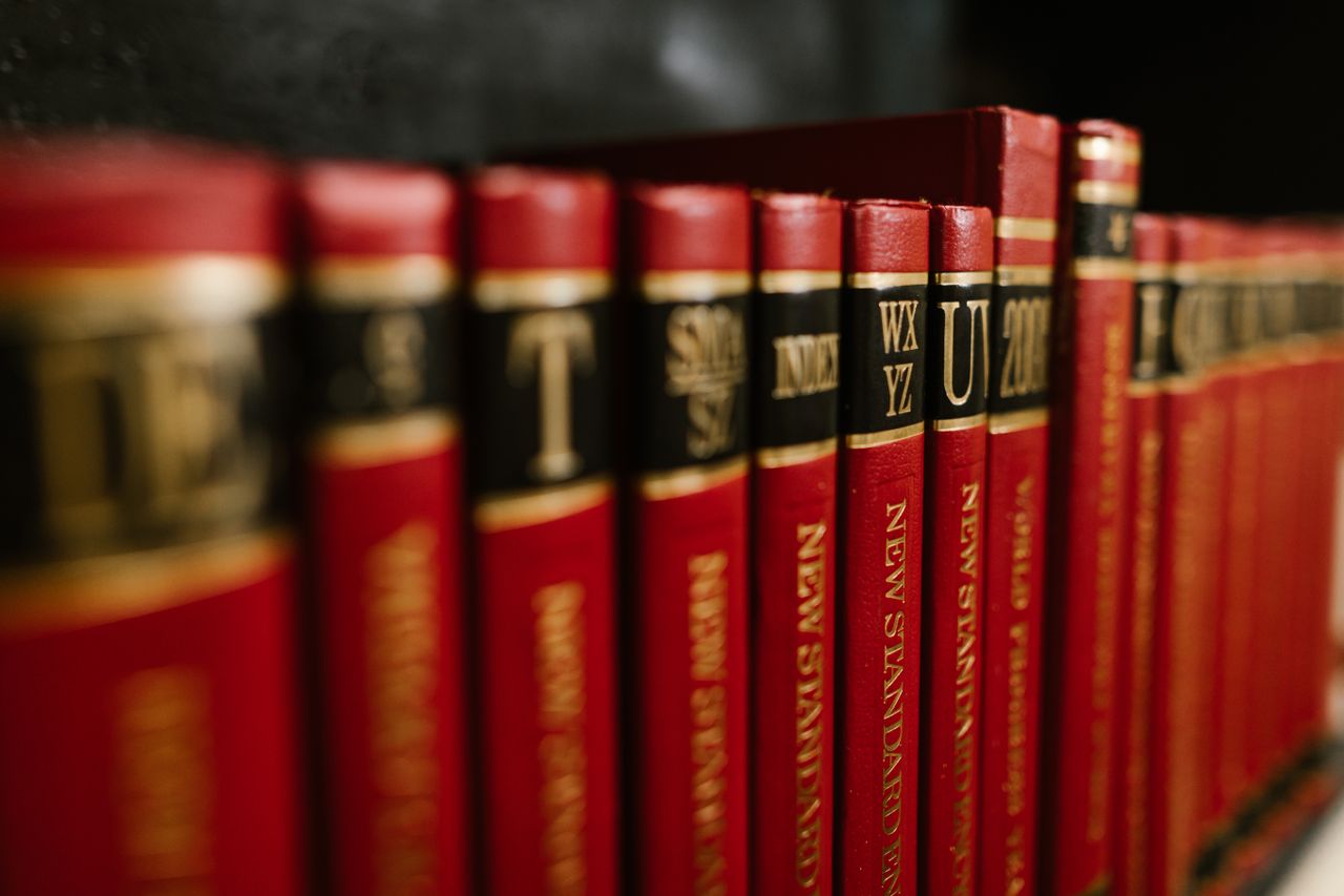 about-story Close-up view of red leather bound encyclopedias on a bookshelf in a library.